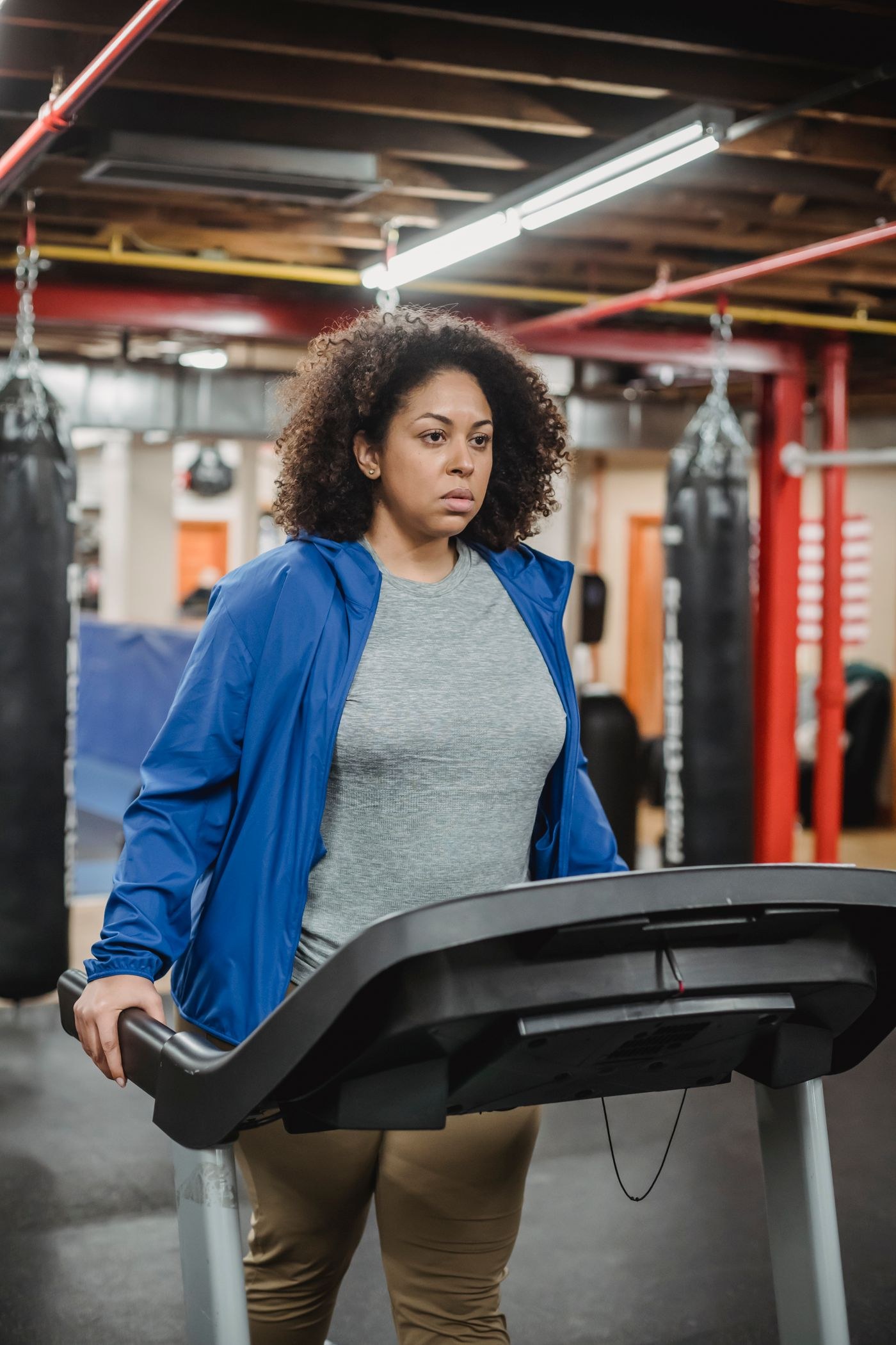 A woman walking at a treadmill console in a gym.