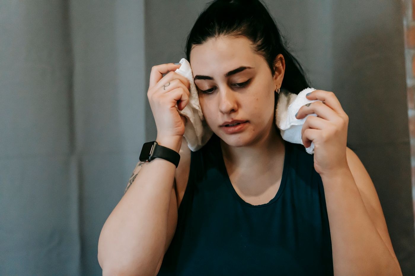 A woman pausing a workout and wiping her face with a towel.