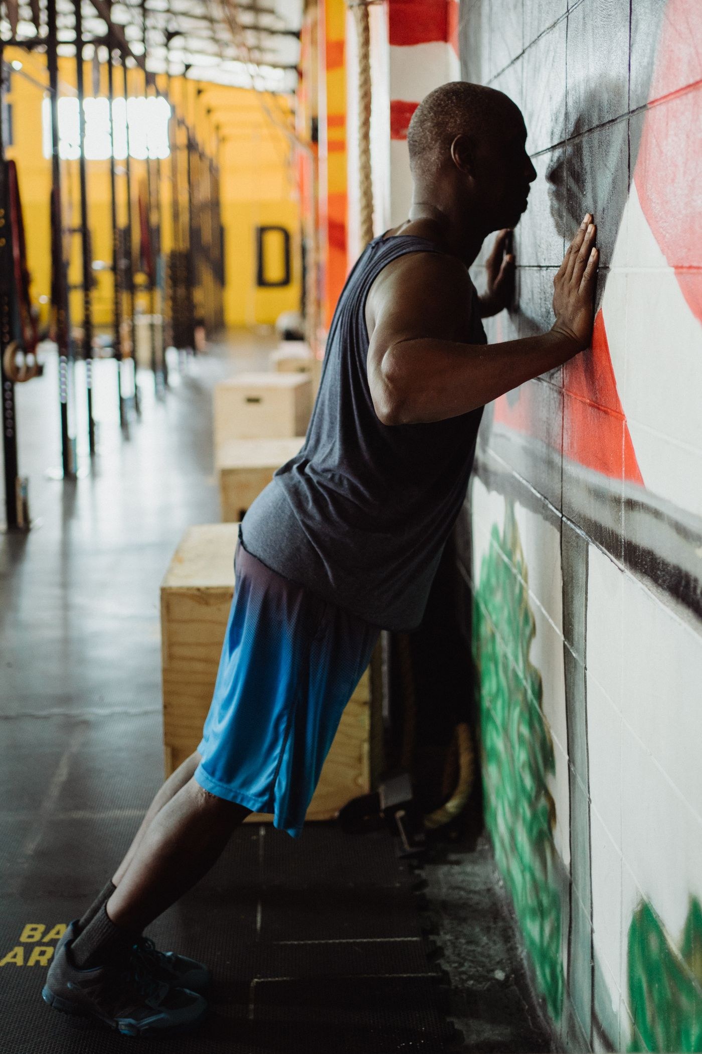 A person standing at an angle to a wall with hands braced for a wall press-up.