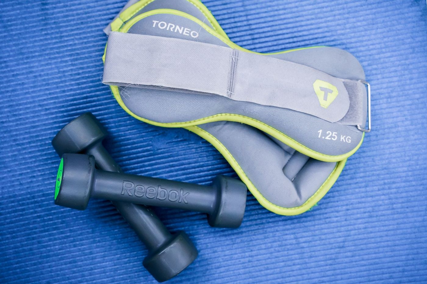 Small dumbbells and ankle weights arranged on an exercise mat.