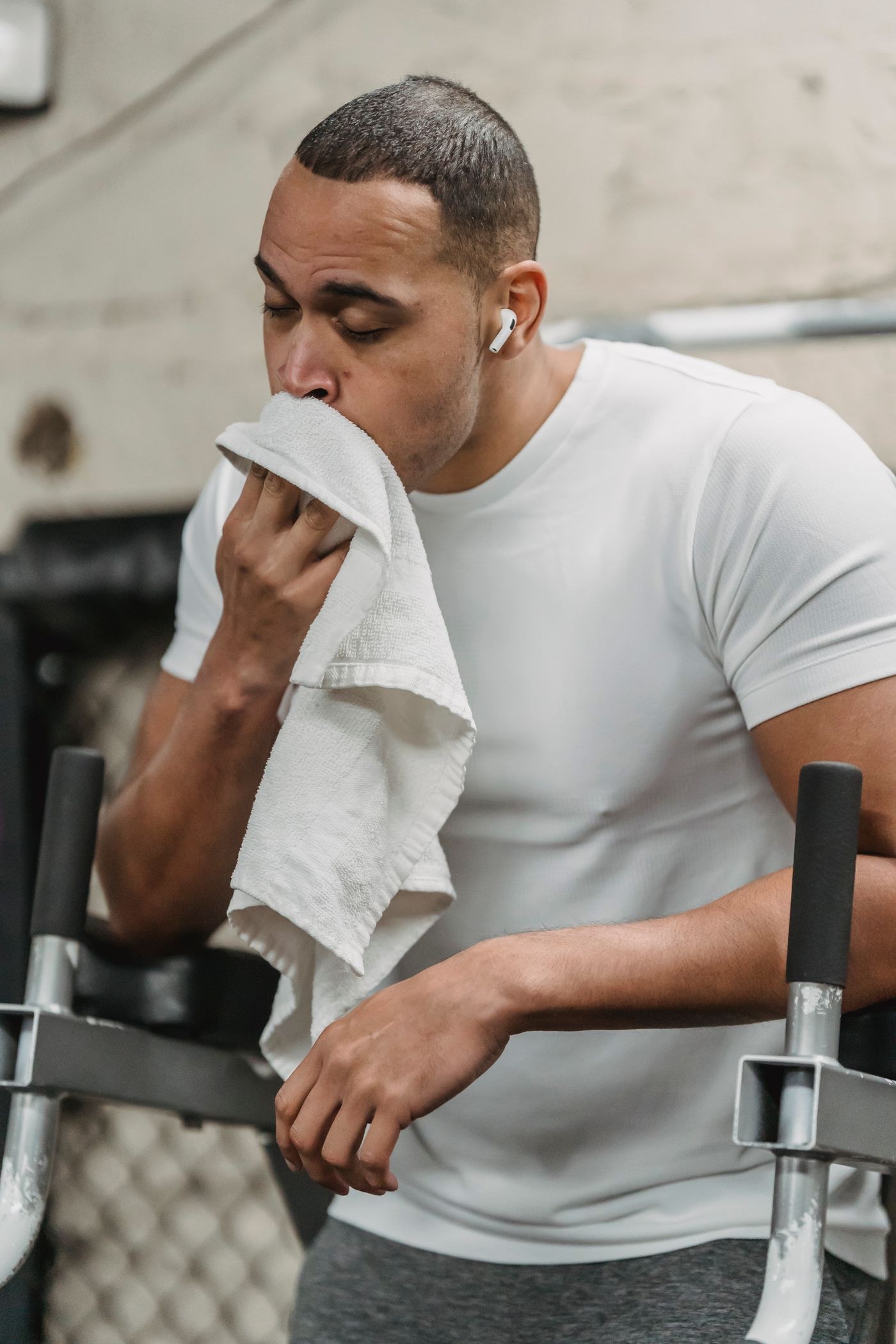 A man wearing wireless earbuds while taking a gym break.