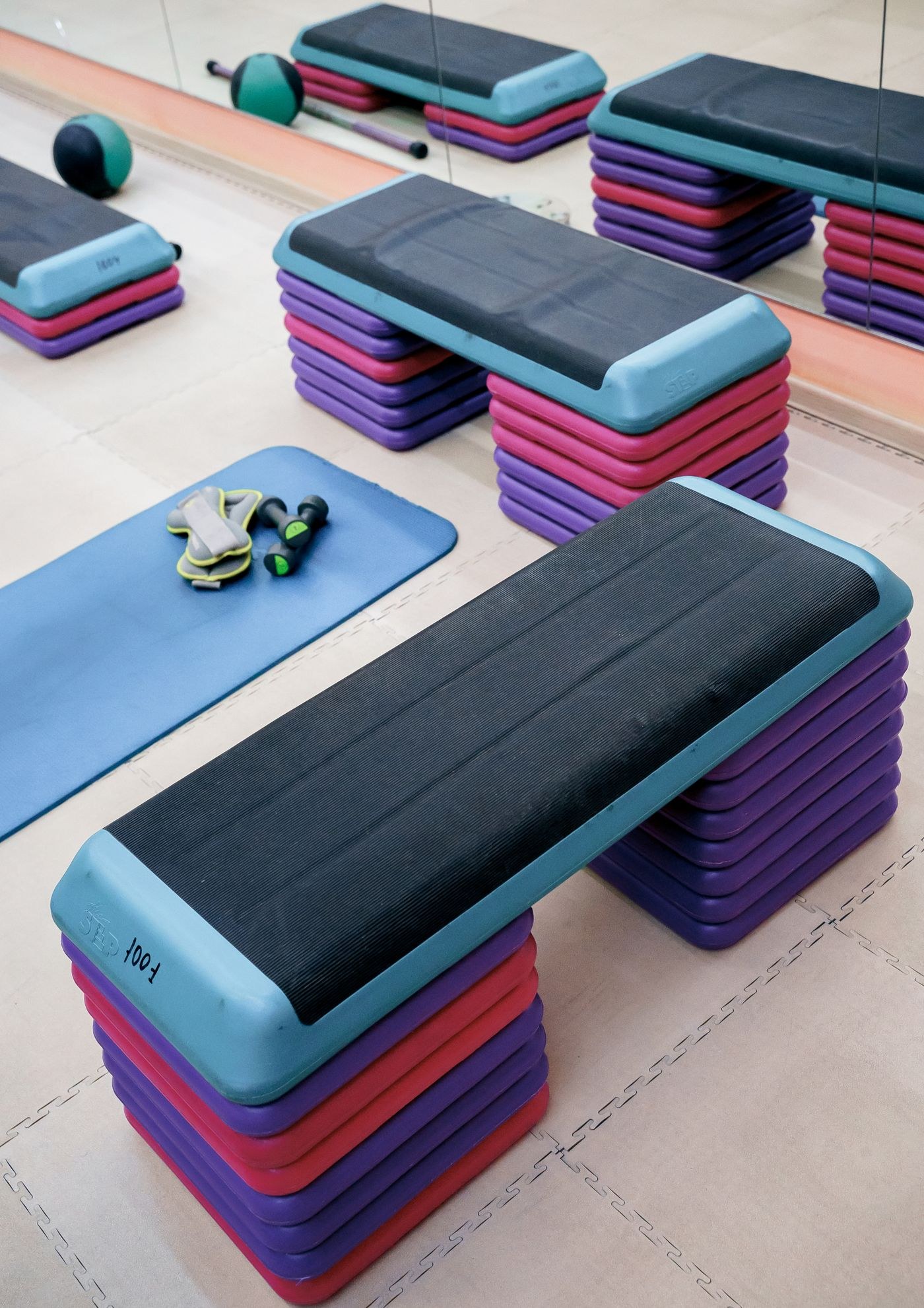 Stackable exercise steps and a mat stored in a studio.