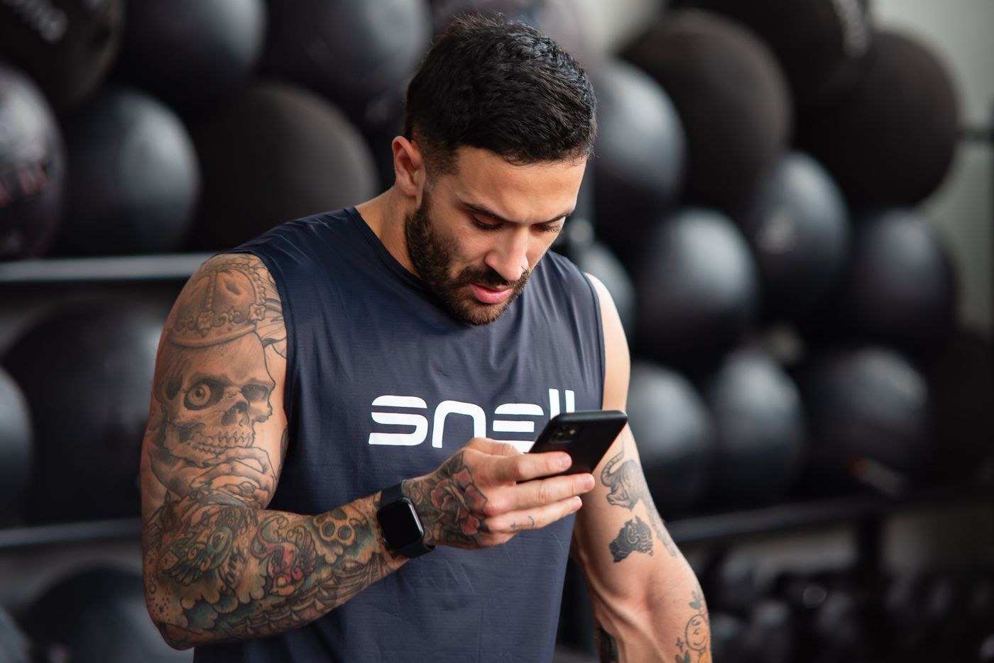 A seated gym user looking down at a smartphone.